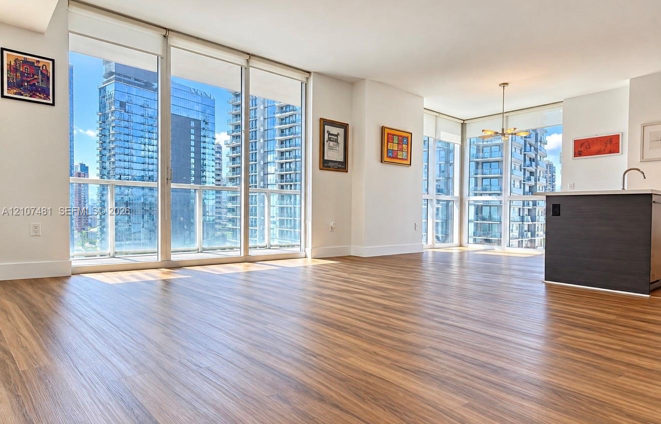 Floor-to-ceiling windows, wood-finish flooring, and kitchen island with a built-in sink Floor-to-ceiling windows, wood-finish flooring, and kitchen island with a built-in sink
