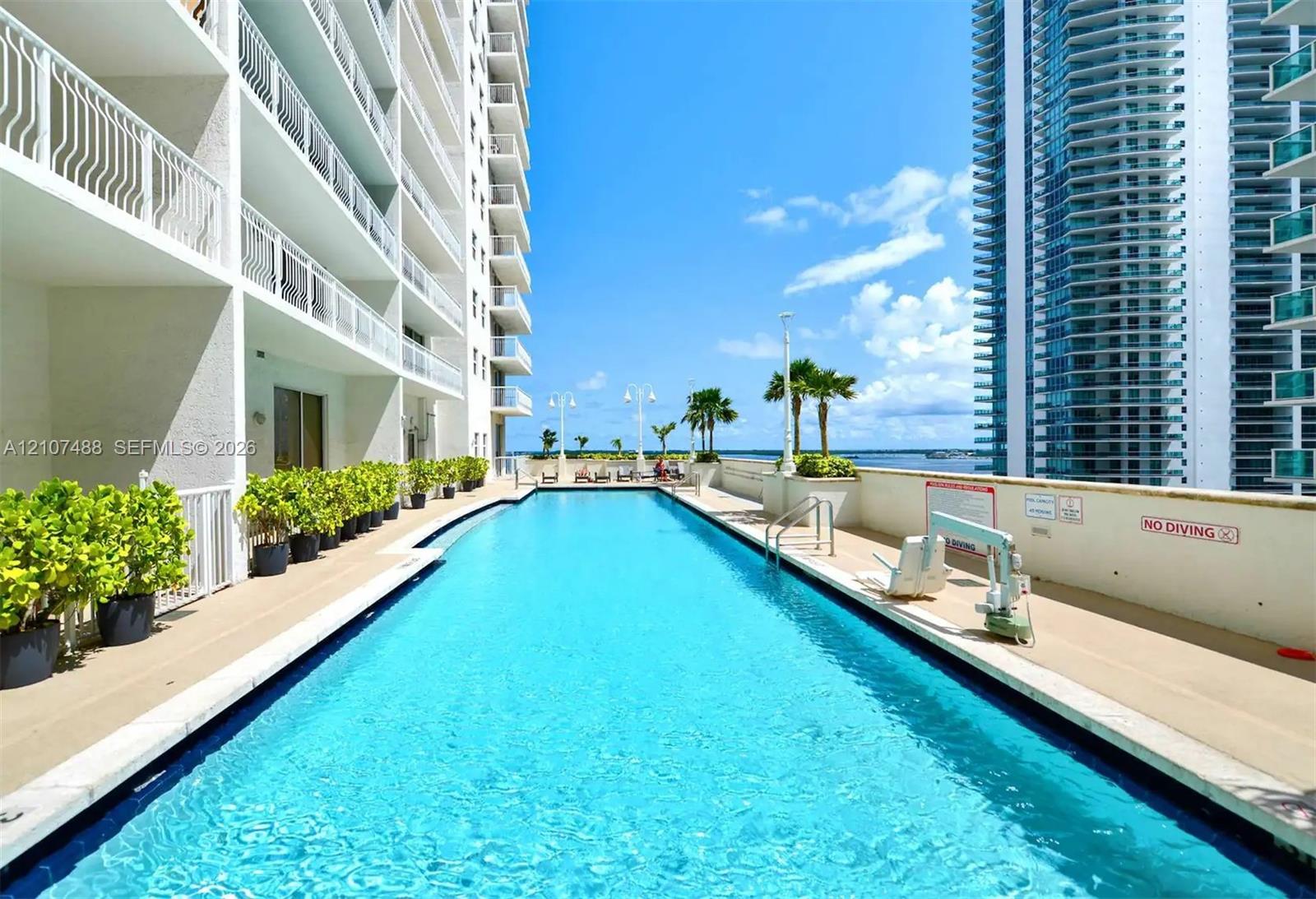 Outdoor swimming pool featuring a concrete deck, metal railings, perimeter planter boxes, and water-level lighting