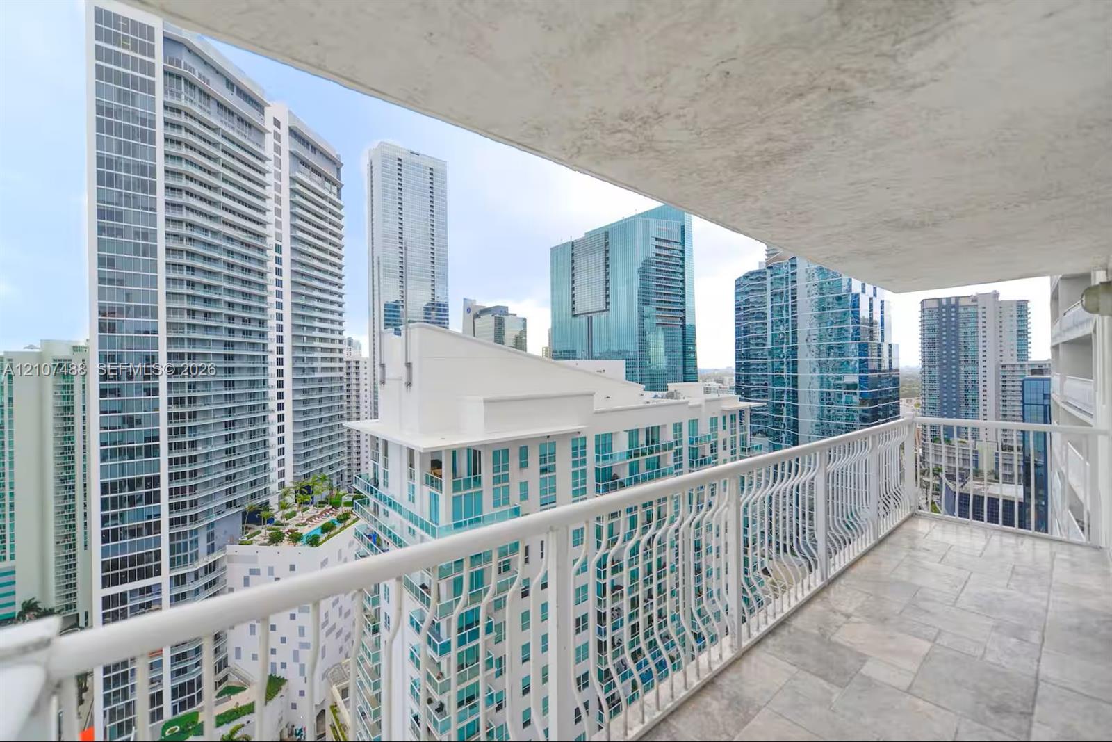 Covered balcony featuring stone tile flooring and a white metal railing