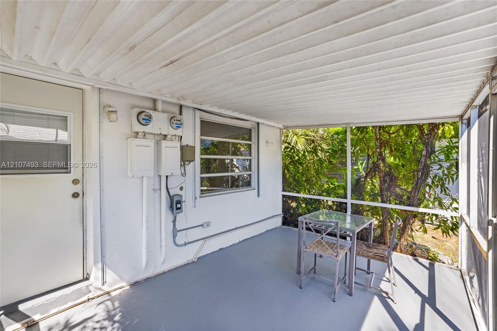 Screened-in porch featuring a corrugated metal ceiling, painted concrete flooring, and horizontal sliding windows