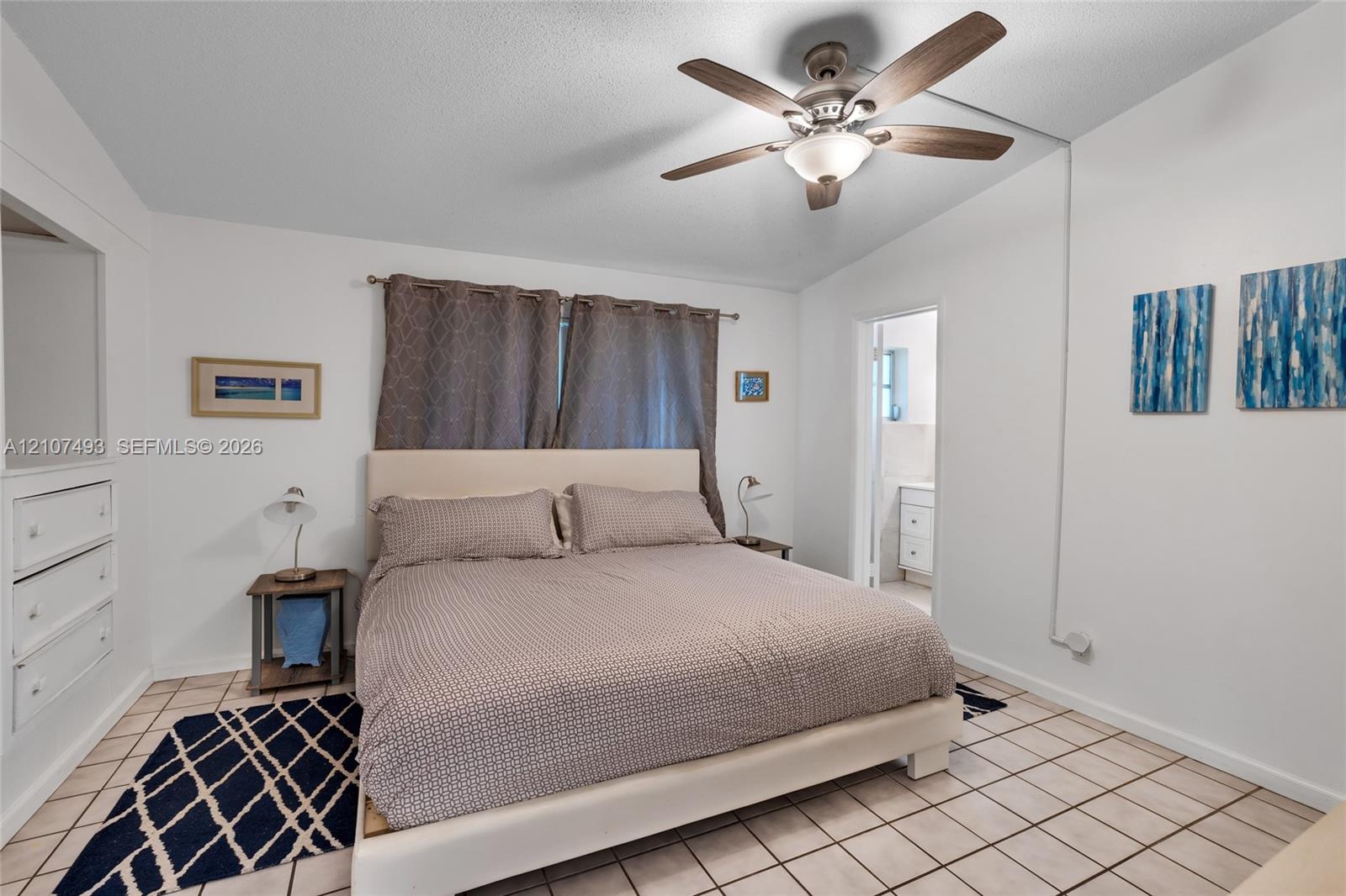 Bedroom featuring tile flooring, ceiling fan with integrated lighting, and built-in cabinetry