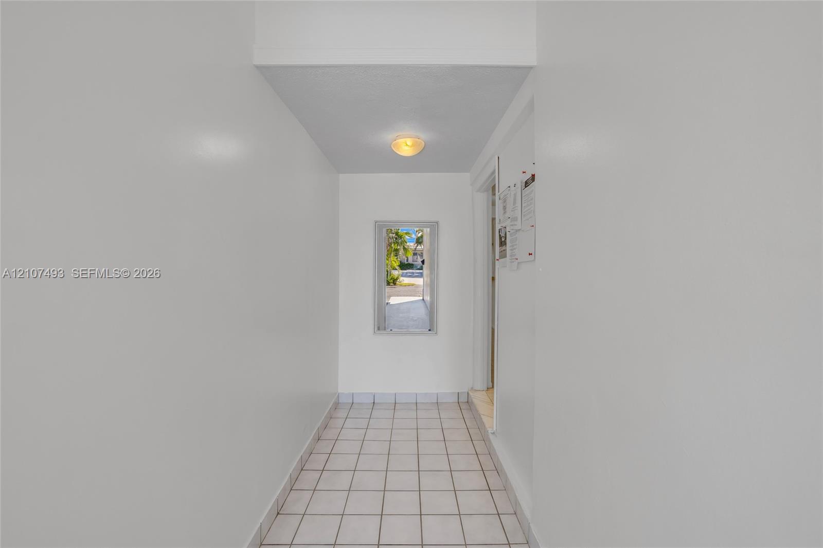 Interior hall featuring white tile flooring, neutral wall finishes, and a flush-mount light fixture