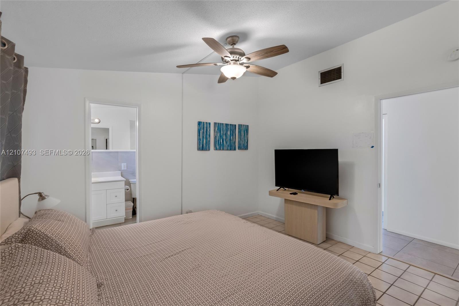 Vaulted ceiling featuring a central multi-blade ceiling fan with integrated light fixture and large-format tile flooring