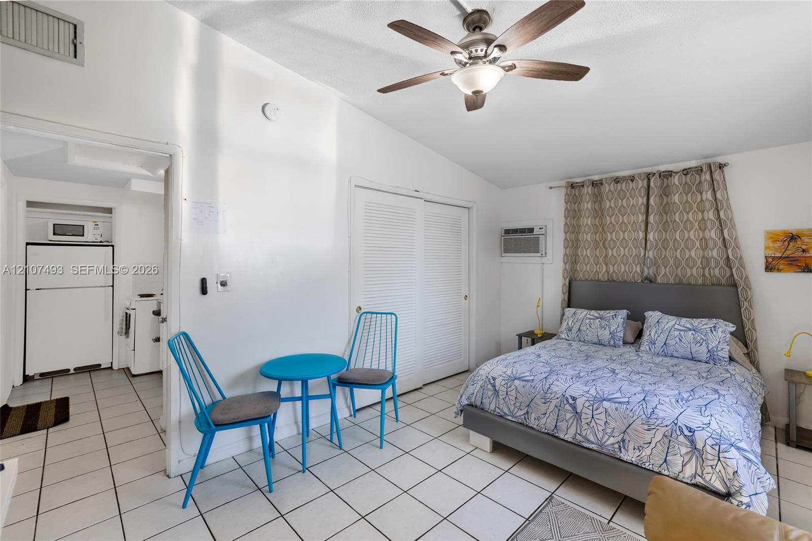 Tile flooring, vaulted ceilings, ceiling fan with integrated lighting, and louvered double-door closet