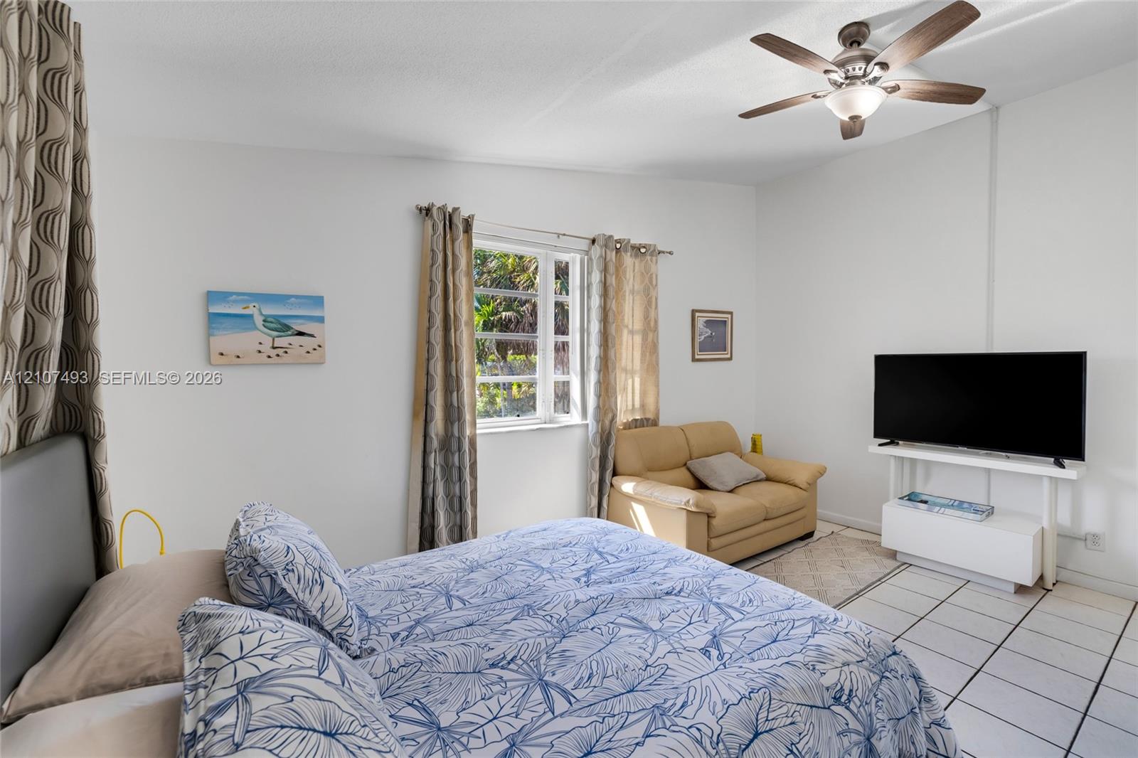 Room featuring ceramic tile flooring, multi-pane window, and ceiling fan with integrated light fixture
