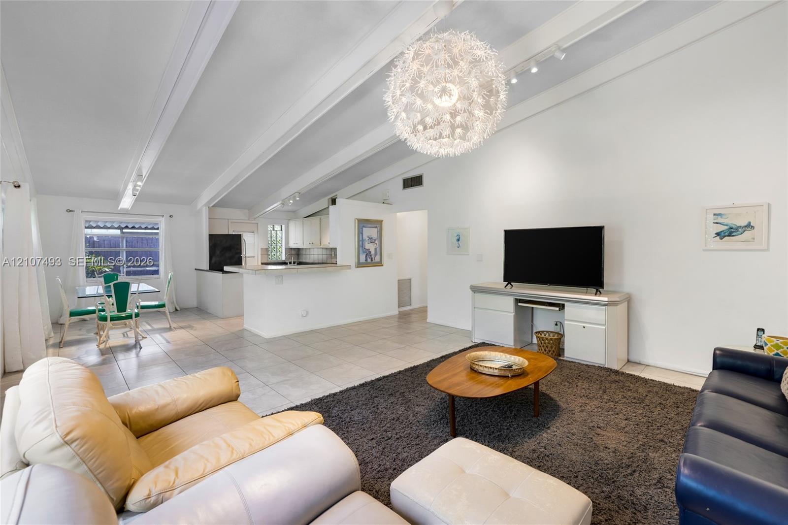 Vaulted ceilings with exposed structural beams, tile flooring, large spherical pendant light fixture, and built-in cabinetry