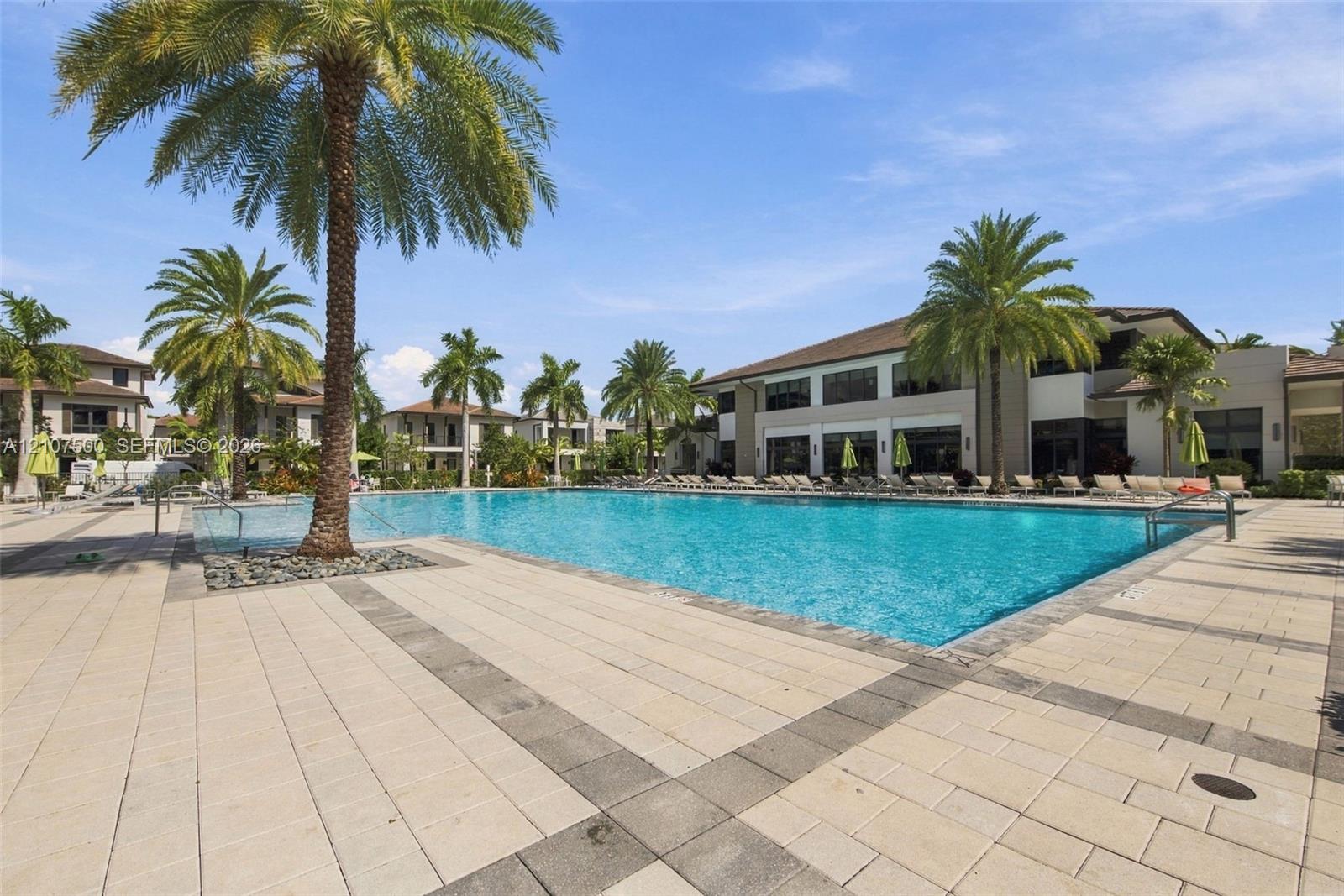 Swimming pool featuring a stone-paver deck, integrated palm trees, and multi-story architecture