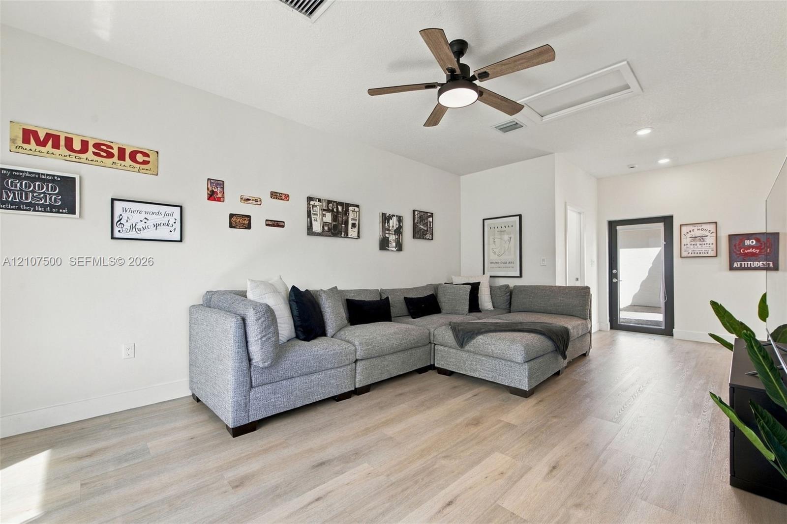 Open-concept interior featuring light wood-finish flooring, recessed lighting, and a modern ceiling fan with integrated lighting