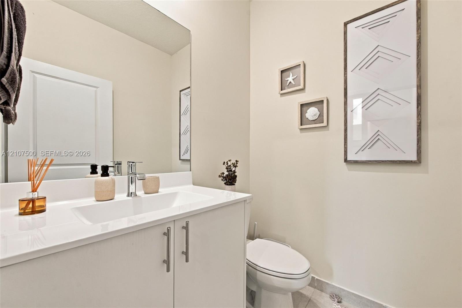 White vanity cabinet with an integrated countertop and sink, chrome single-handle faucet, and large wall-mounted mirror