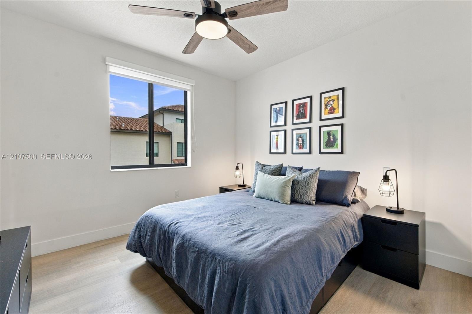 Neutral-toned walls, wood-finish flooring, a contemporary ceiling fan with integrated lighting, and a window with a dark-finish frame