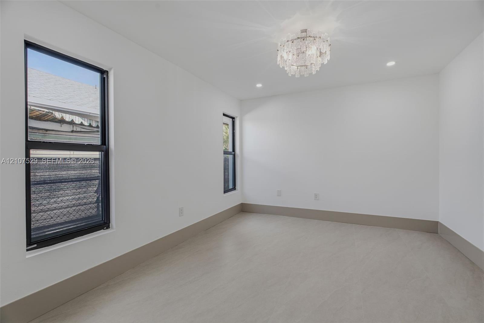 Neutral-toned tile flooring, recessed lighting, ornate central pendant fixture, black-framed windows, and built-in closet with panel doors