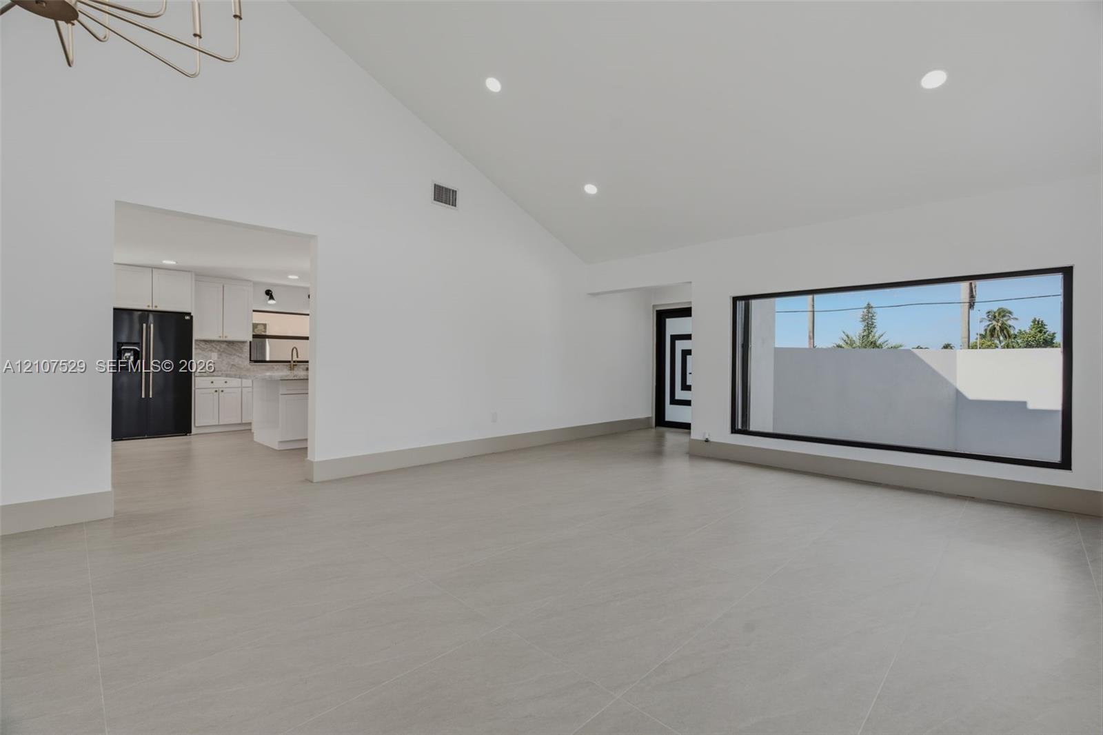 Private patio featuring large-format tile flooring, high perimeter masonry walls, a dark metal privacy fence, and wood-finish ceiling soffit