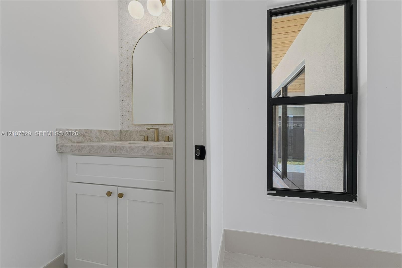 Interior space featuring large-format tile flooring, a two-panel door with matte black hardware, and an elongated porcelain toilet