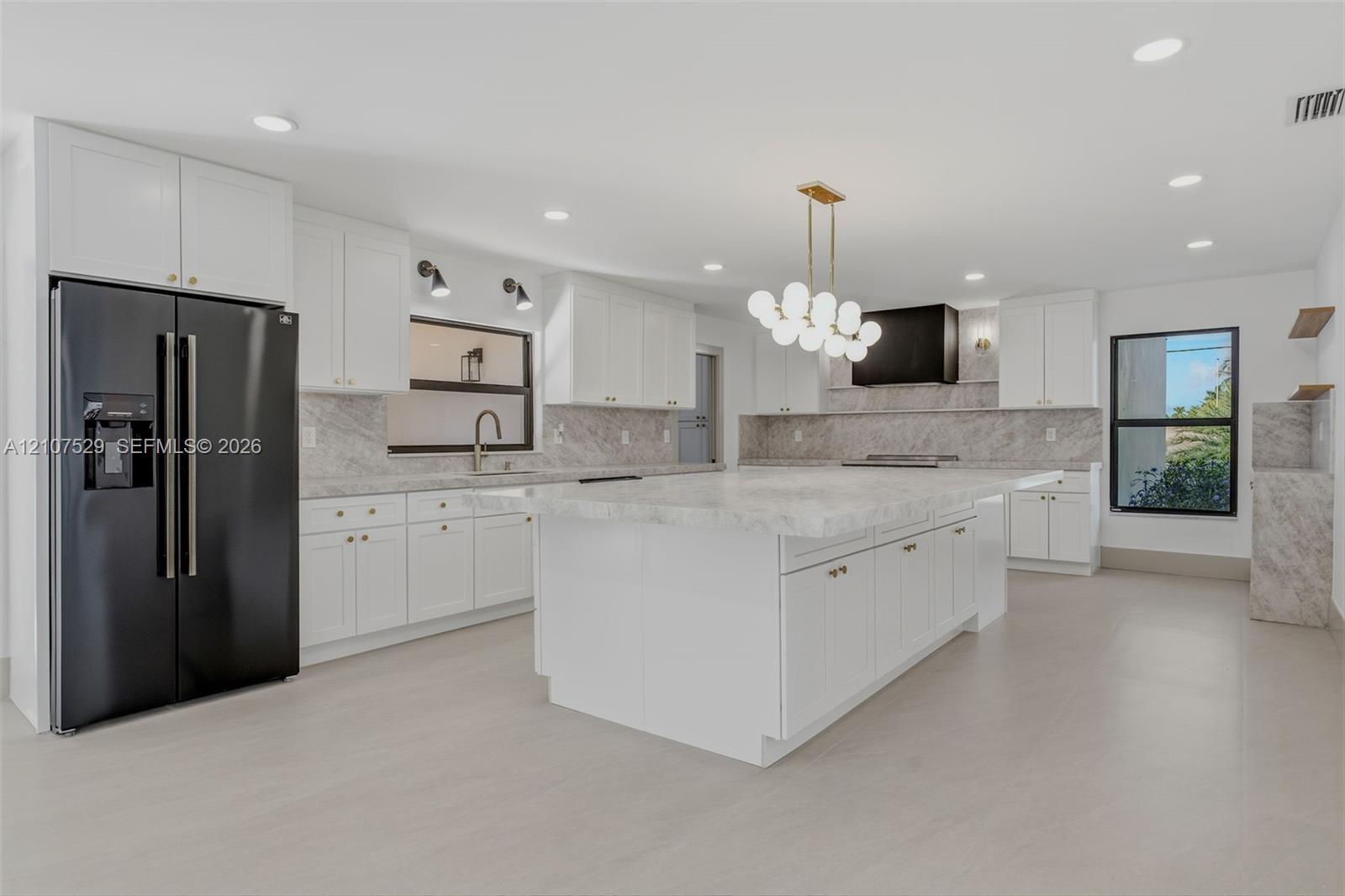 Kitchen featuring white shaker cabinetry, stone-finish countertops and backsplash, black range with matching vent hood, and natural wood floating shelves