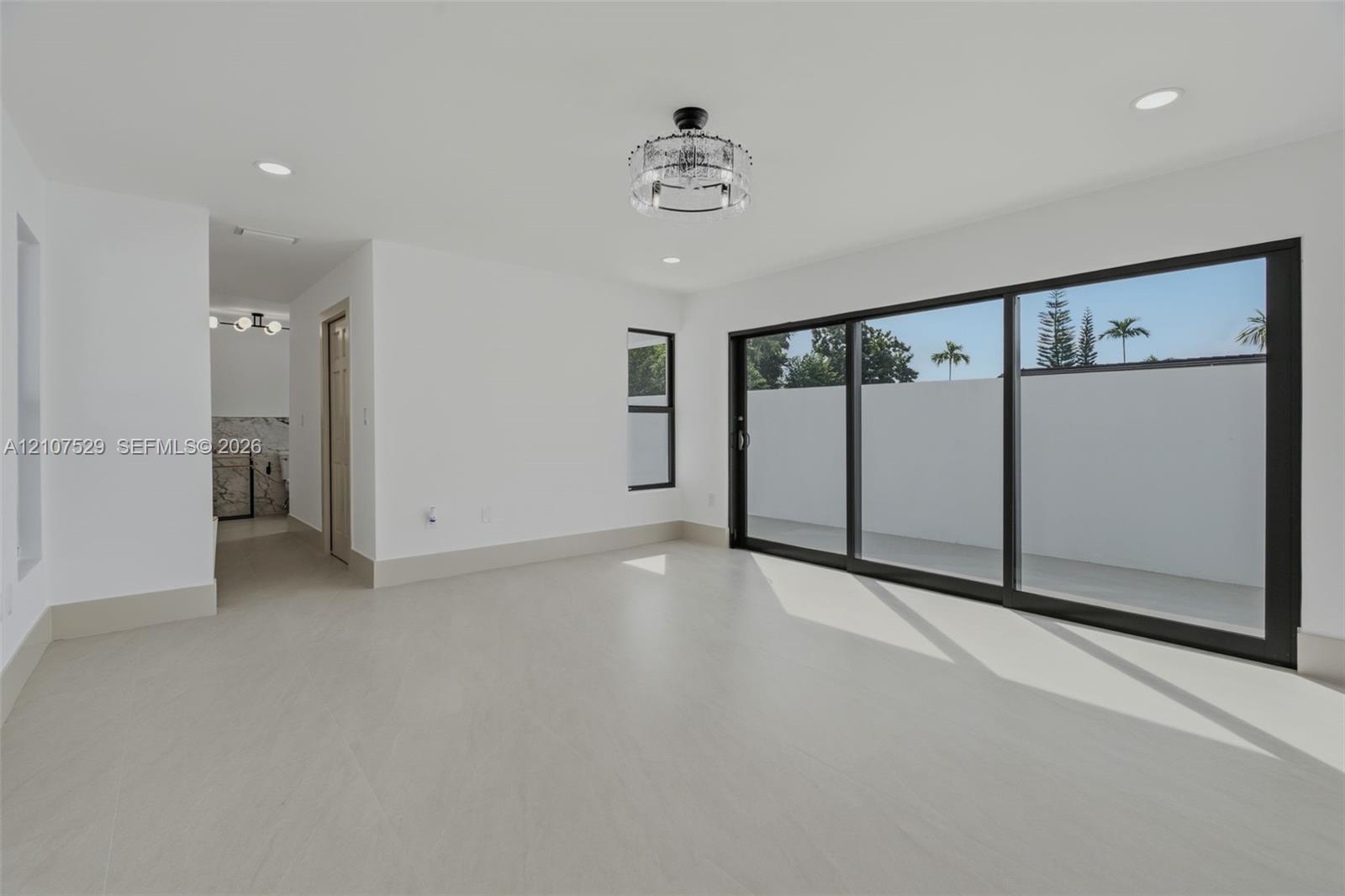 Spacious interior featuring large-format tile flooring, recessed lighting, a modern drum-style flush mount ceiling fixture, and black-trimmed windows