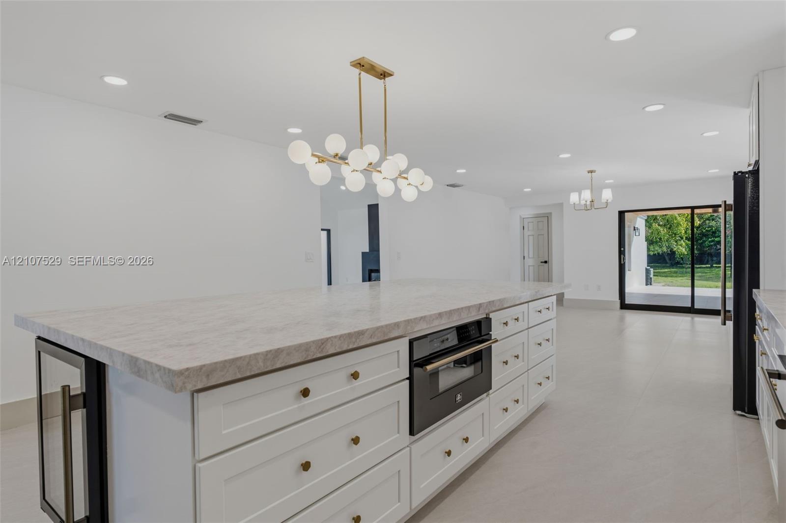 Neutral-toned flooring, multi-light chandelier, recessed ceiling lighting, and expansive glass sliding doors with black frames