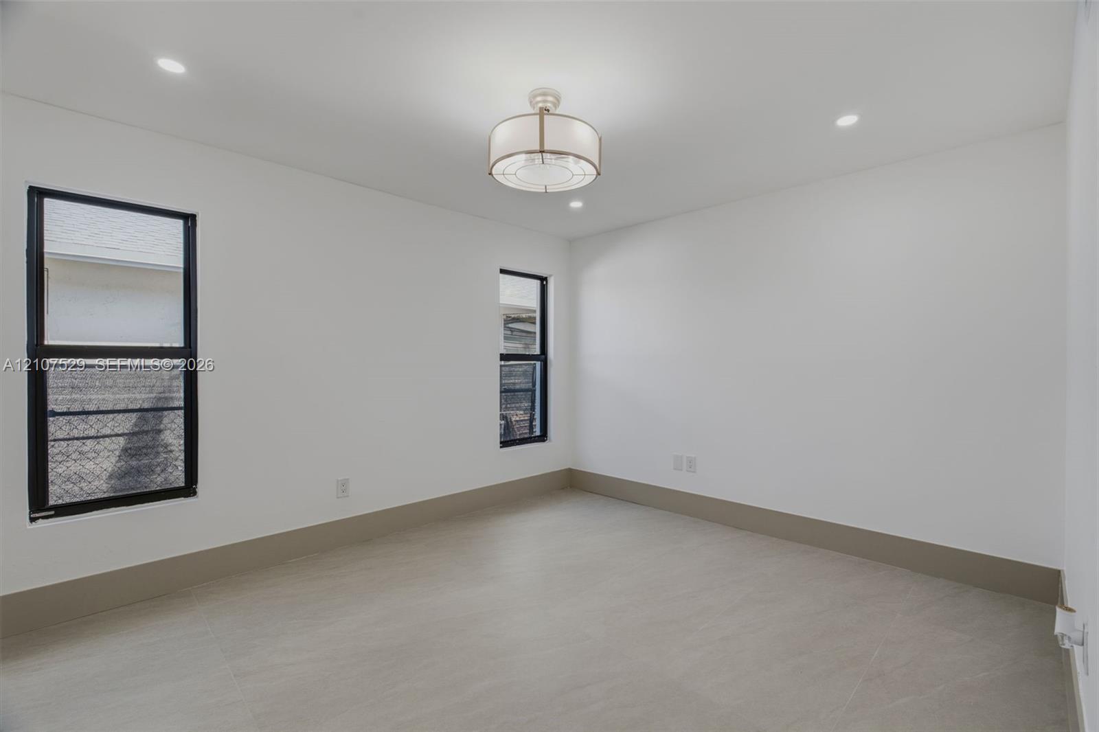 Neutral-toned room featuring a tiered crystal chandelier, wood-finish flooring, recessed lighting, double-panel sliding closet doors, and black-framed windows