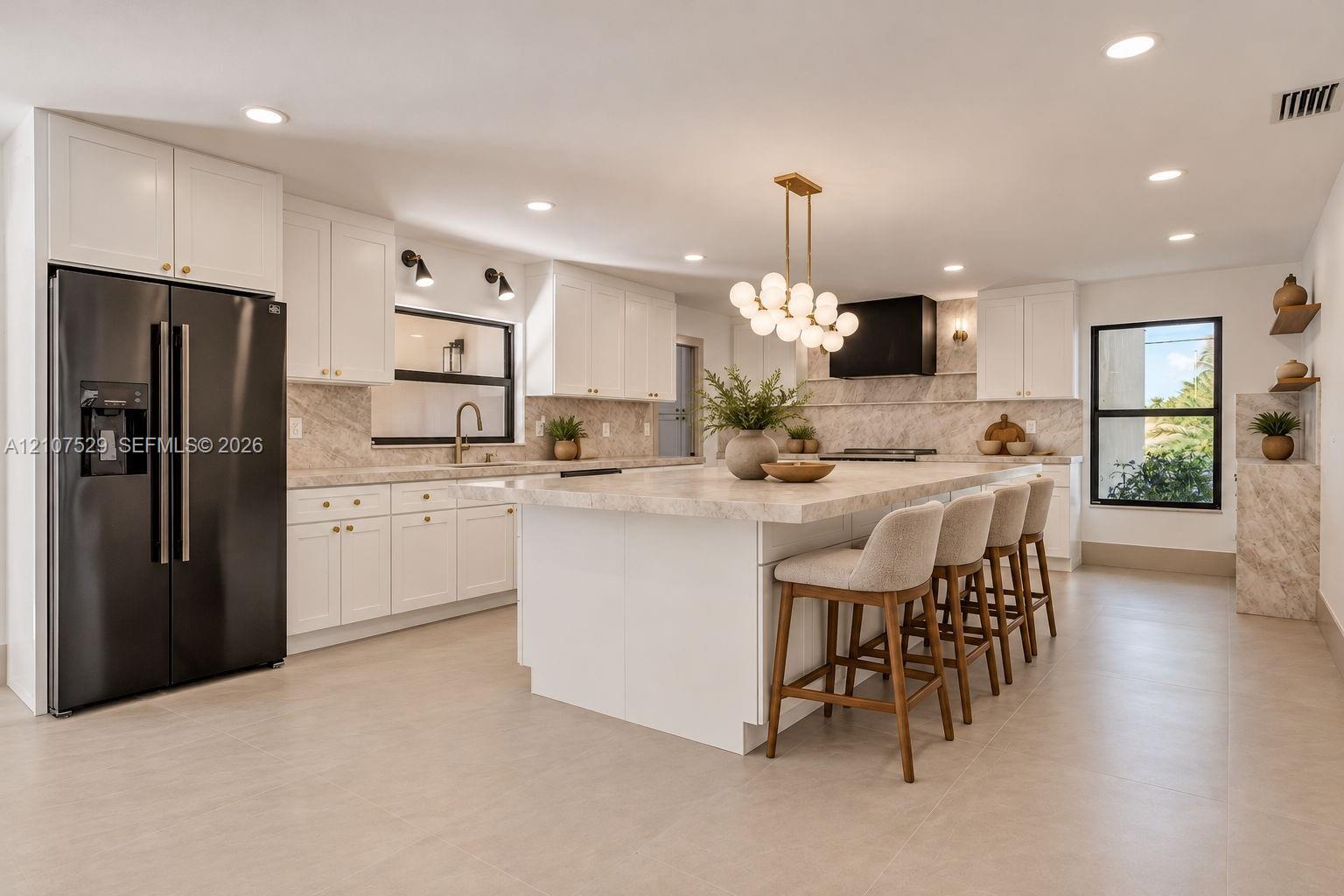 Kitchen featuring shaker-style cabinetry, an expansive center island with stone-finish countertops, matte black appliances, modern multi-globe chandelier lighting, and large-format tile flooring