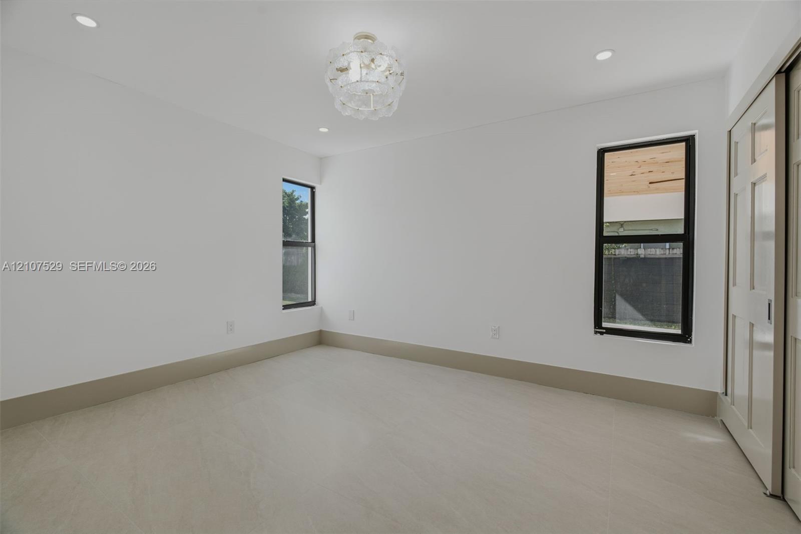 Neutral-toned tile flooring, multi-pane sliding closet doors, decorative multi-tiered pendant lighting, and recessed ceiling illumination