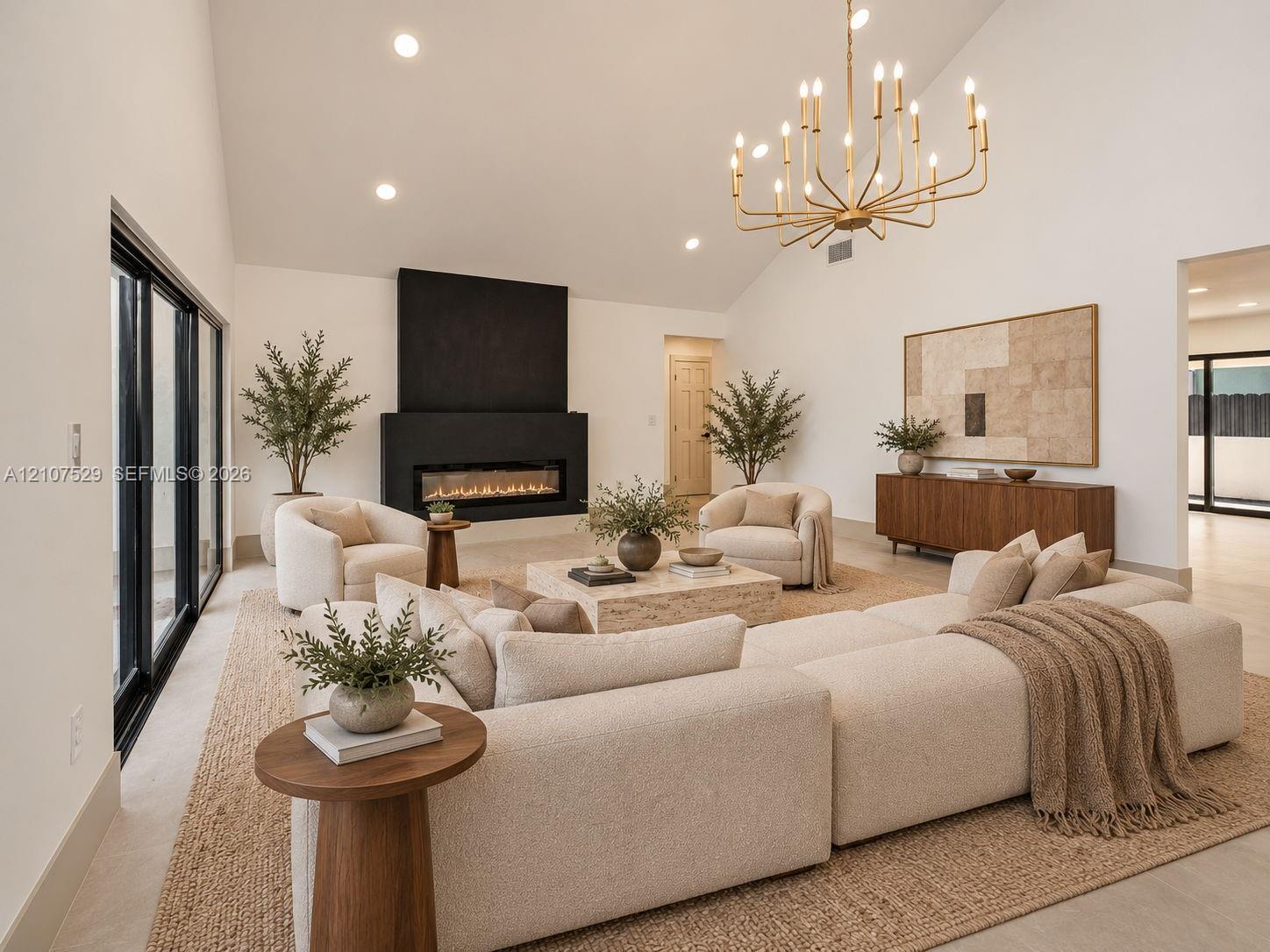 Vaulted ceiling with recessed lighting, floor-to-ceiling black-framed windows, linear fireplace with a matte black surround, and metal multi-tier chandelier