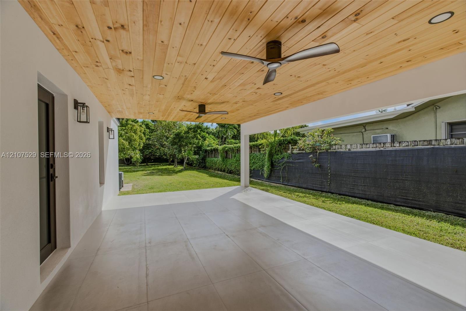 Covered patio featuring a natural wood-plank ceiling, recessed lighting, ceiling fan, expansive tile flooring, and large-format sliding glass doors
