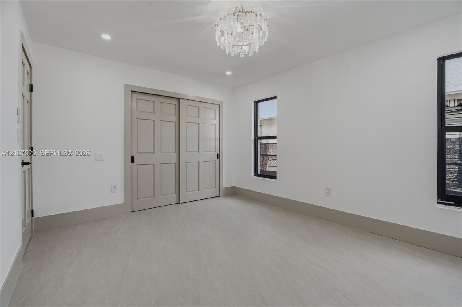 Interior space featuring light-toned tile flooring, neutral walls, a tiered crystal-style flush mount ceiling fixture, and recessed lighting