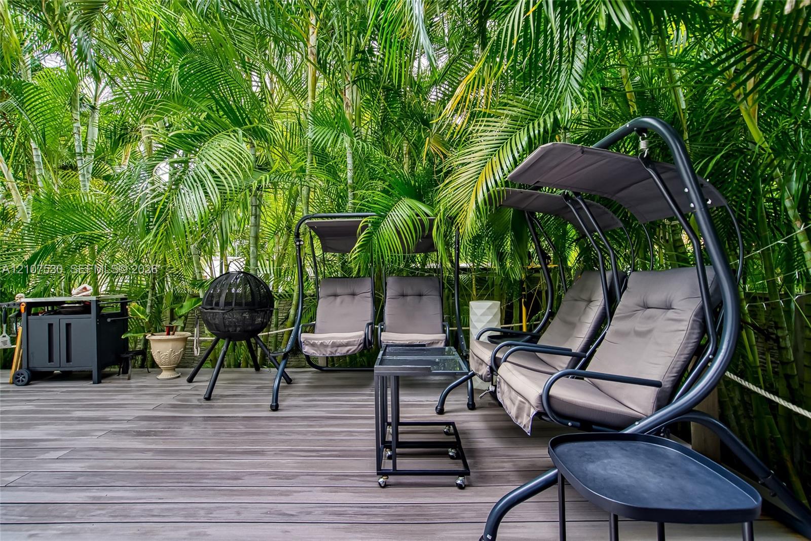 Outdoor deck featuring wood-finish composite planking and mature tropical foliage