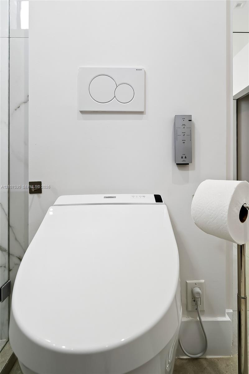 Wall-mounted, dual-flush actuator plate, electronic smart toilet with integrated control panel, and adjacent marble-patterned tile wall finish