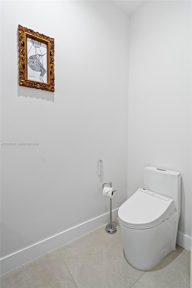 High-efficiency toilet with an integrated electronic bidet seat and large-format tile flooring