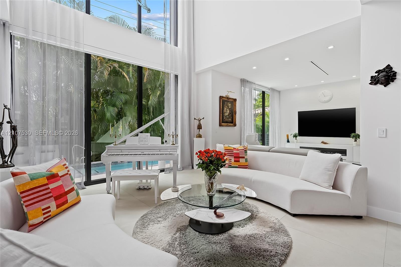Double-height ceilings, floor-to-ceiling glass wall, recessed lighting, and large-format tile flooring