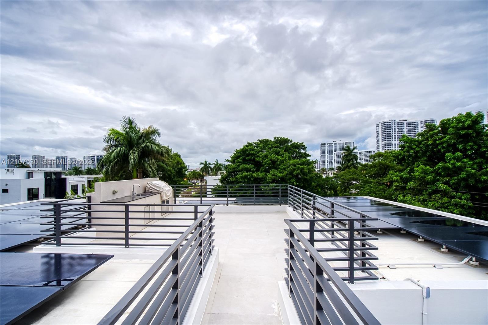 Rooftop terrace featuring light-colored flooring, metal railings, and a built-in outdoor wet bar