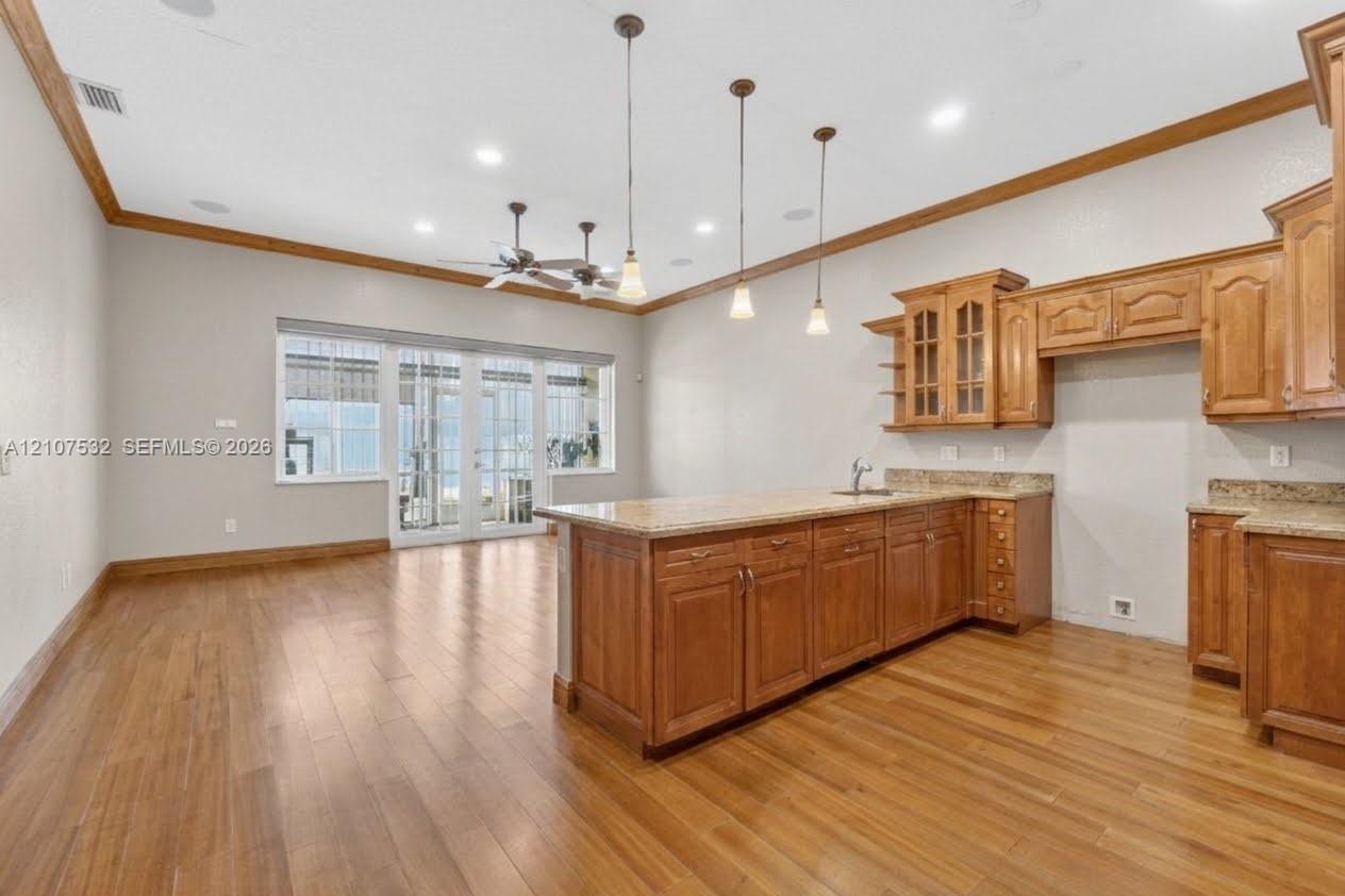 Kitchen featuring wood-finish cabinetry, stone countertops, pendant lighting, recessed lighting, and wood-finish flooring