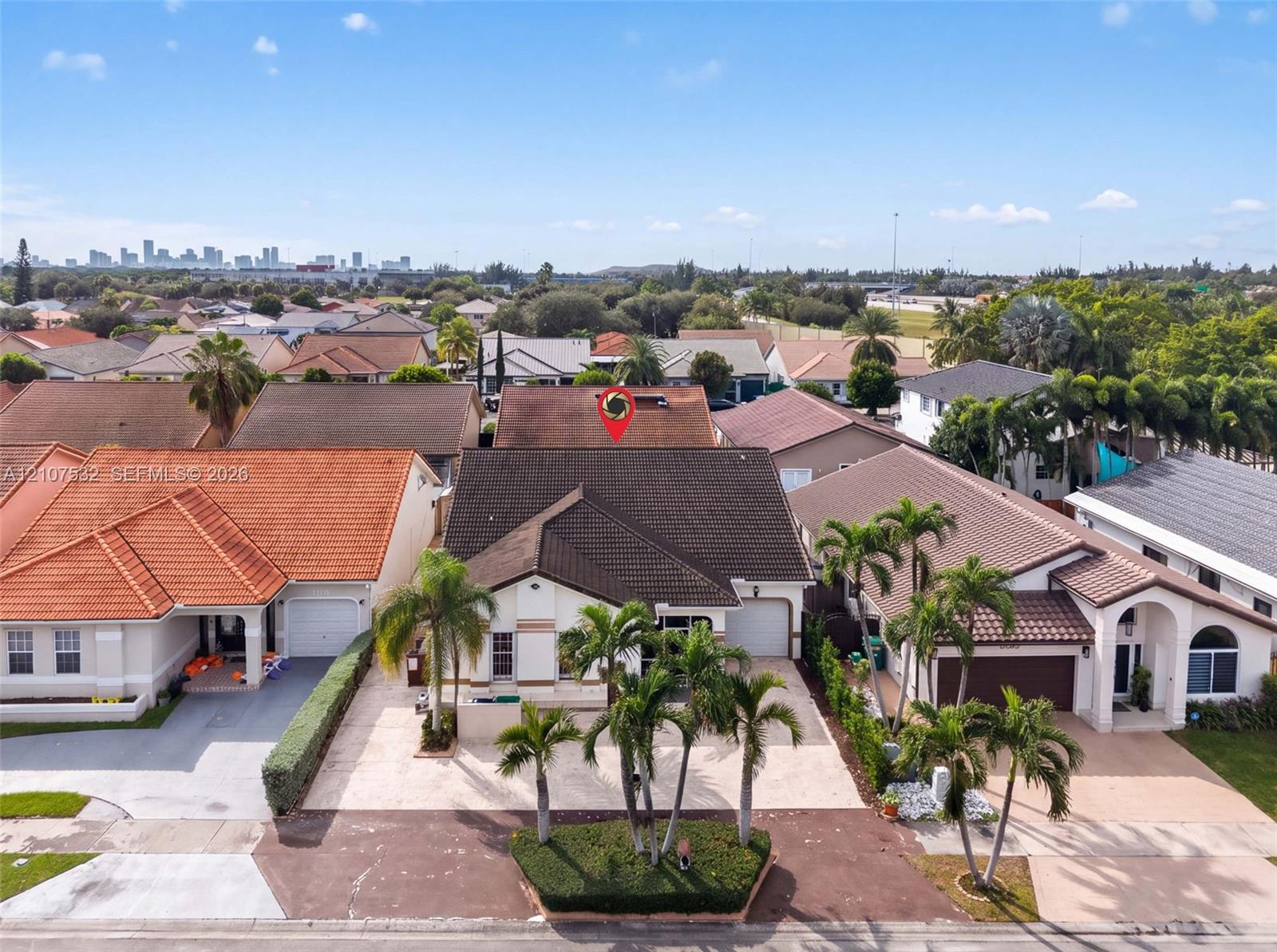 Single-story residence featuring a tile roof, paved driveway, one-car garage, and established palm tree landscaping Single-story residence featuring a tile roof, paved driveway, one-car garage, and established palm tree landscaping