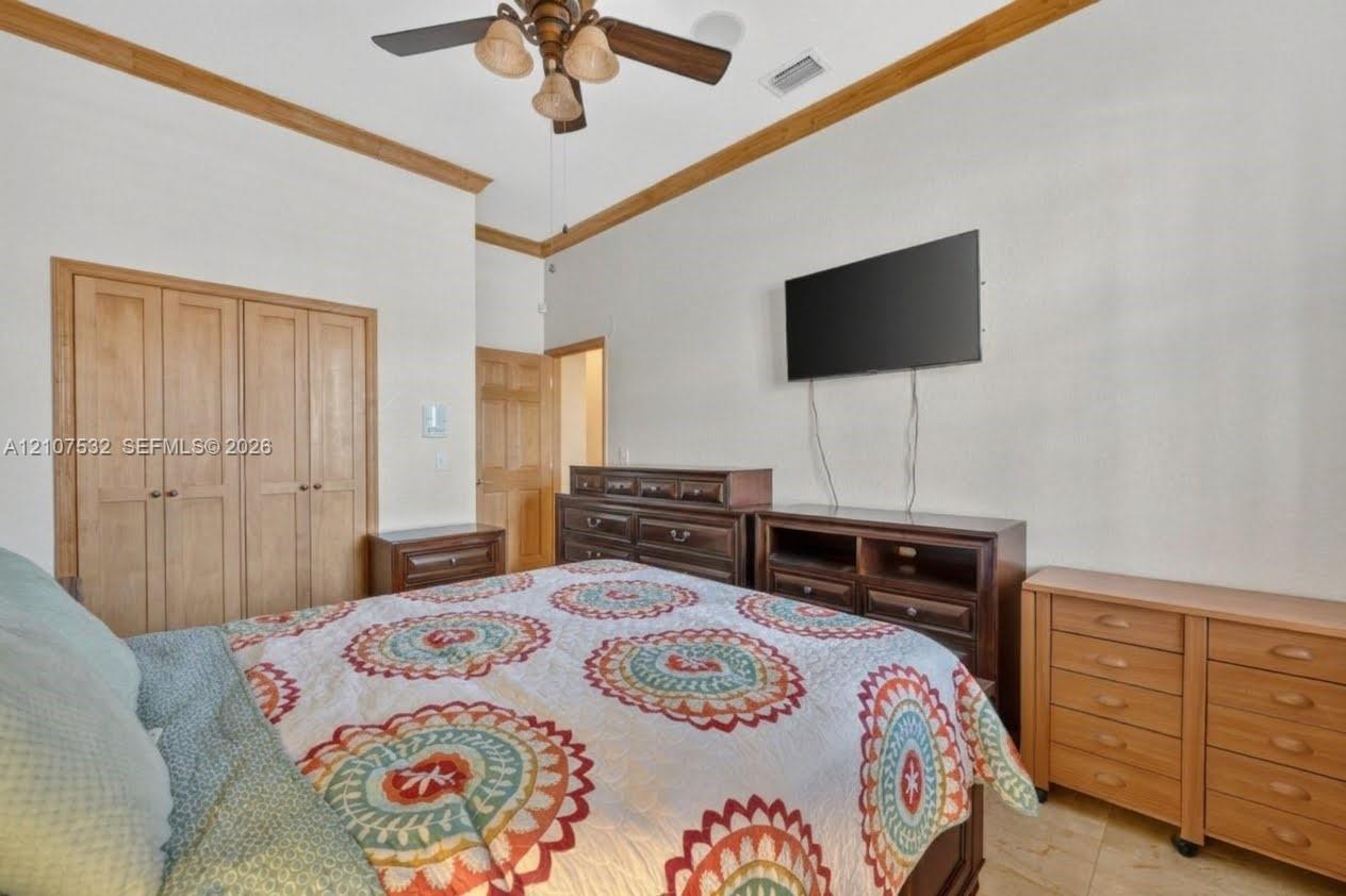 Room featuring crown molding, multi-panel wood doors, tile flooring, and a ceiling fan with integrated lighting Room featuring crown molding, multi-panel wood doors, tile flooring, and a ceiling fan with integrated lighting