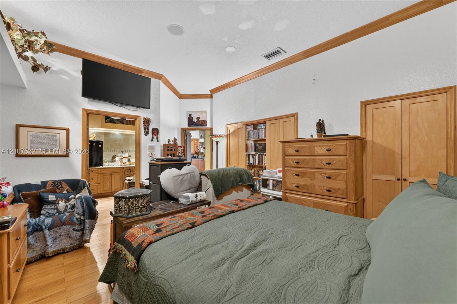 Vaulted ceilings featuring natural wood crown molding, wood-finish flooring, and built-in wooden cabinetry Vaulted ceilings featuring natural wood crown molding, wood-finish flooring, and built-in wooden cabinetry