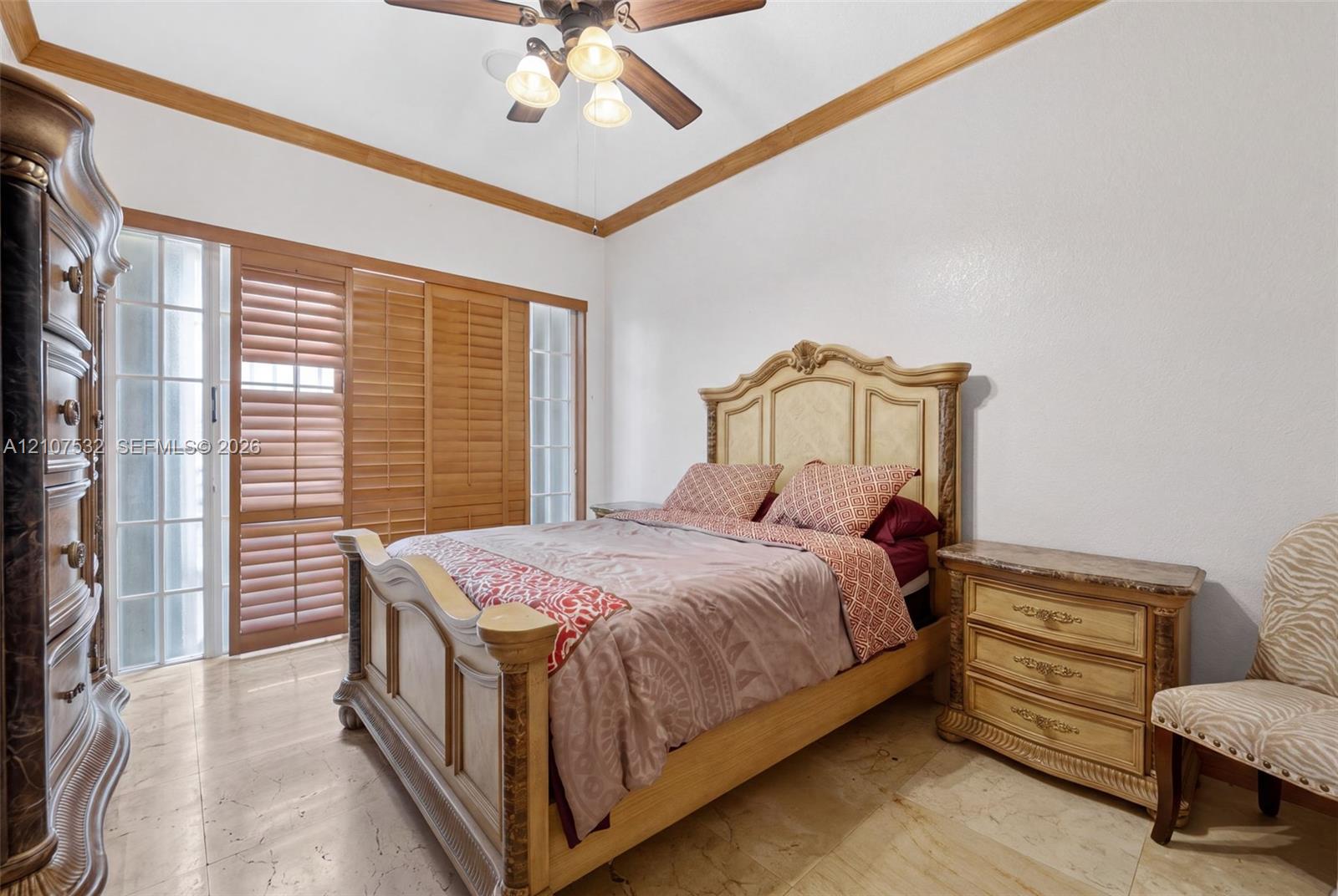 Tray ceiling with crown molding, natural stone flooring, and built-in sliding wood-slat closet doors with sidelight windows Tray ceiling with crown molding, natural stone flooring, and built-in sliding wood-slat closet doors with sidelight windows