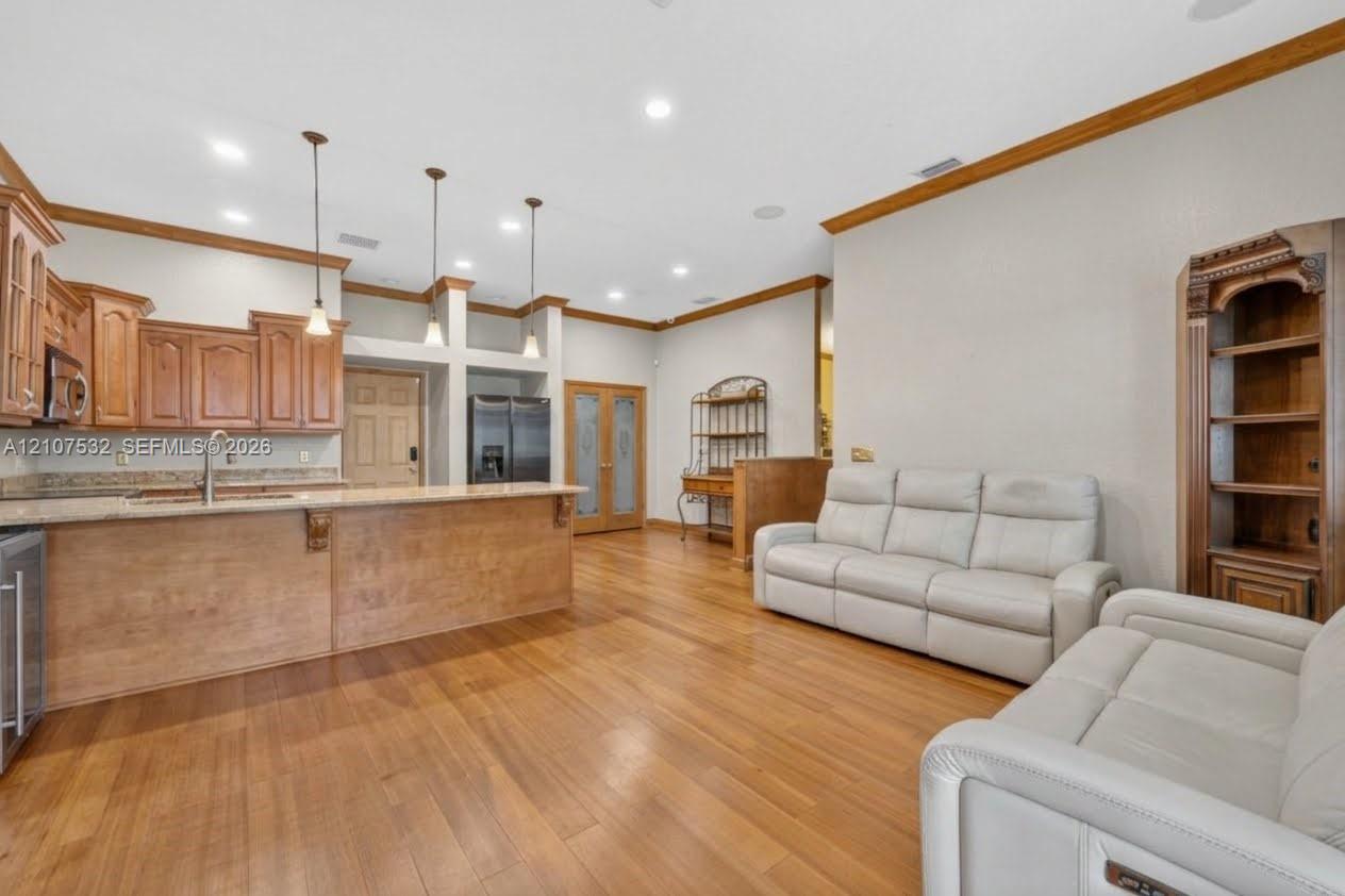 Kitchen featuring wood-finish cabinetry, stone-surface countertops, pendant lighting, built-in shelving, and wood-finish flooring