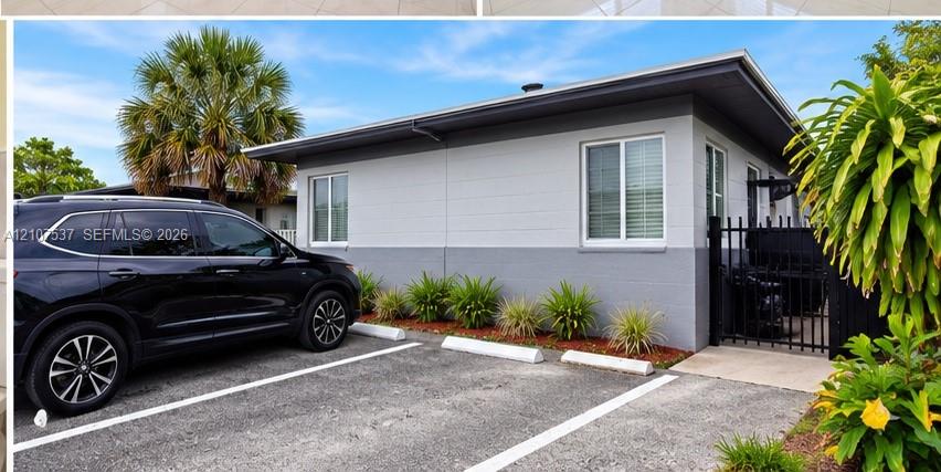 Two-tone painted masonry exterior featuring designated paved parking, sliding windows, and a black metal gated entryway Two-tone painted masonry exterior featuring designated paved parking, sliding windows, and a black metal gated entryway