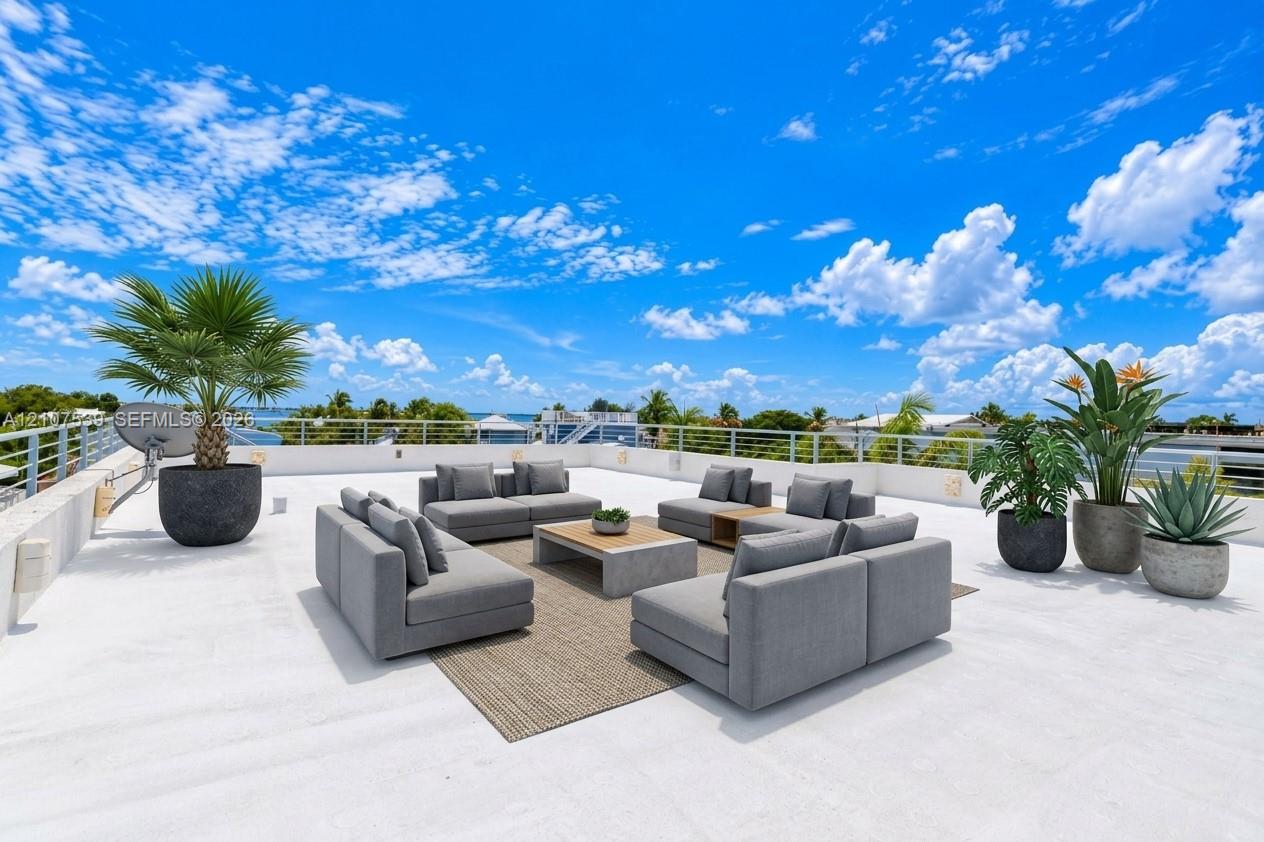 Expansive rooftop terrace featuring white flat surfacing, horizontal cable railings, and wall-mounted exterior lighting
