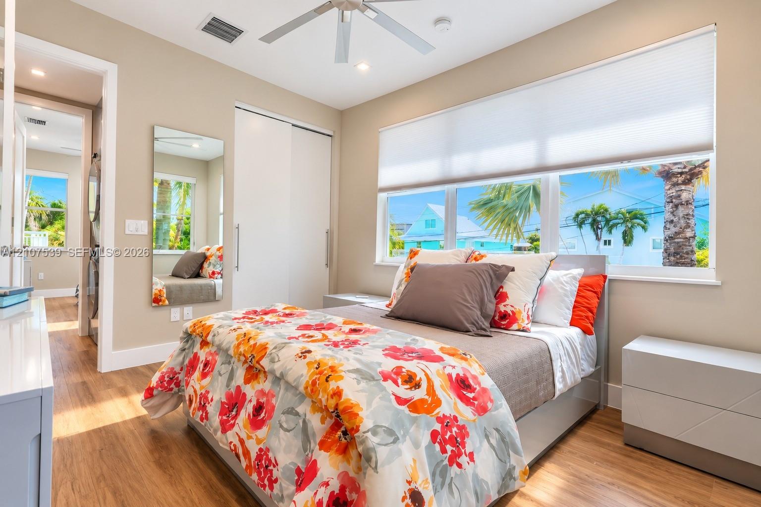 Wood-finish flooring, large sliding closet with integrated door hardware, ceiling fan with light fixture, and horizontal window treatments