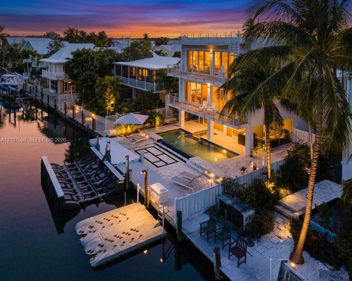 Three-story waterfront residence featuring multi-level balconies, a stone-surround swimming pool, and a private dock with boat lift