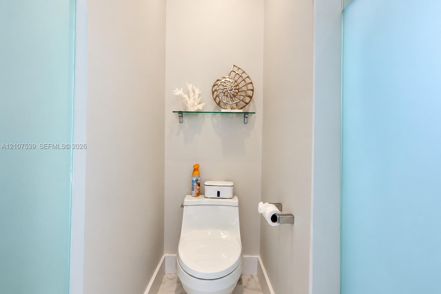 Wall-mounted glass shelving, one-piece dual-flush toilet, and frosted glass privacy panels