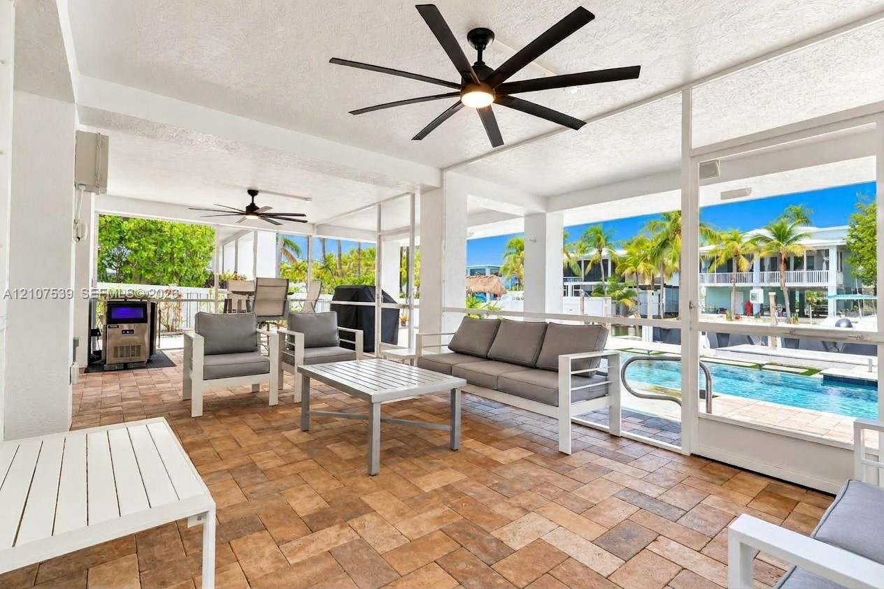 Screened-in lanai featuring paver flooring, multiple multi-blade ceiling fans, and a direct perimeter enclosure overlooking the pool area