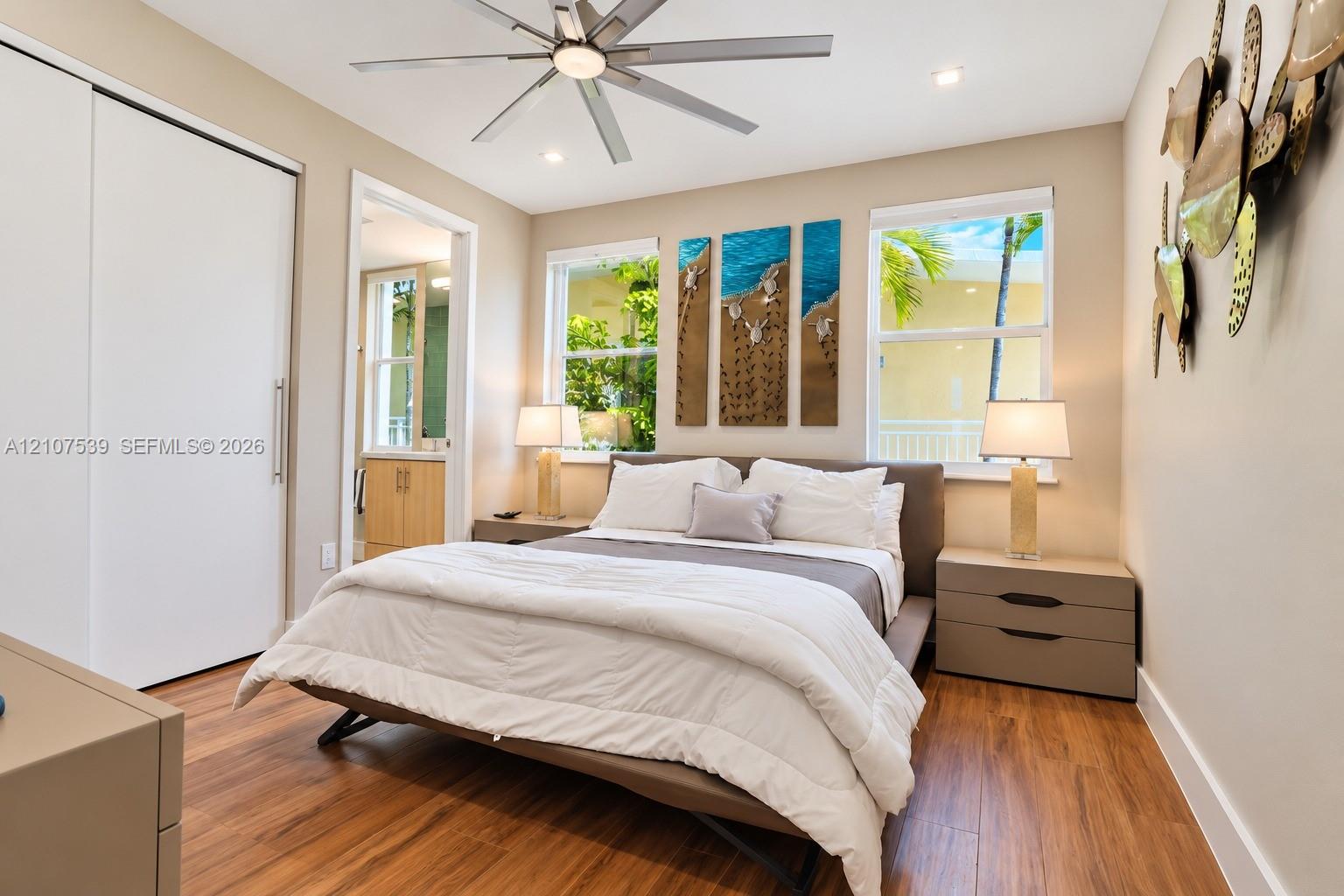 Wood-finish flooring, recessed lighting, ceiling fan, sliding closet doors, and windows with exterior greenery
