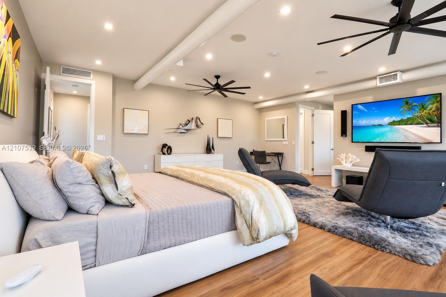 Spacious room featuring wood-finish flooring, recessed lighting, industrial-style exposed ductwork, and dual modern ceiling fans