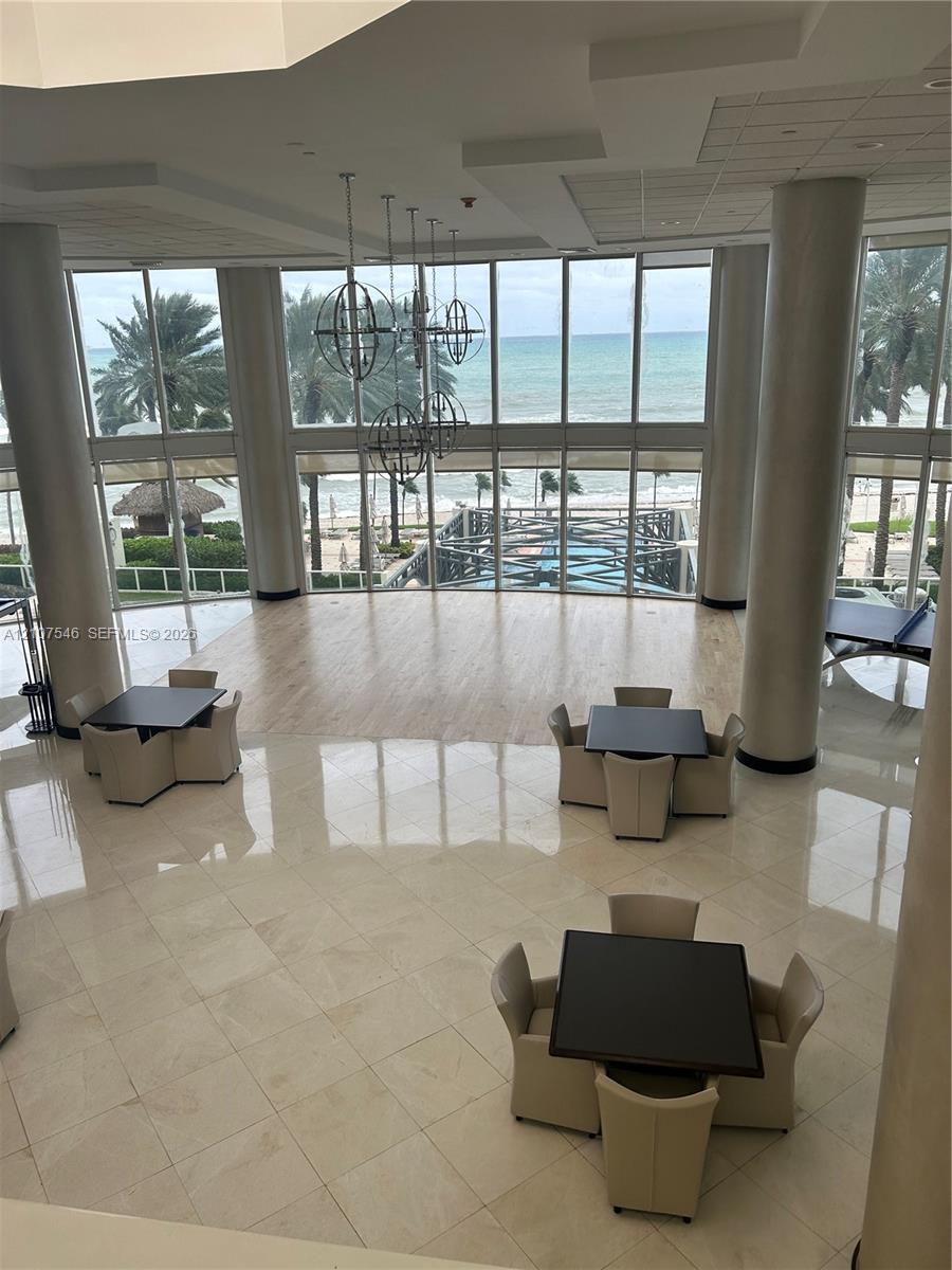 Double-height floor-to-ceiling windows, polished tile flooring, wood-finish flooring accents, structural cylindrical columns, and metal orb pendant lighting