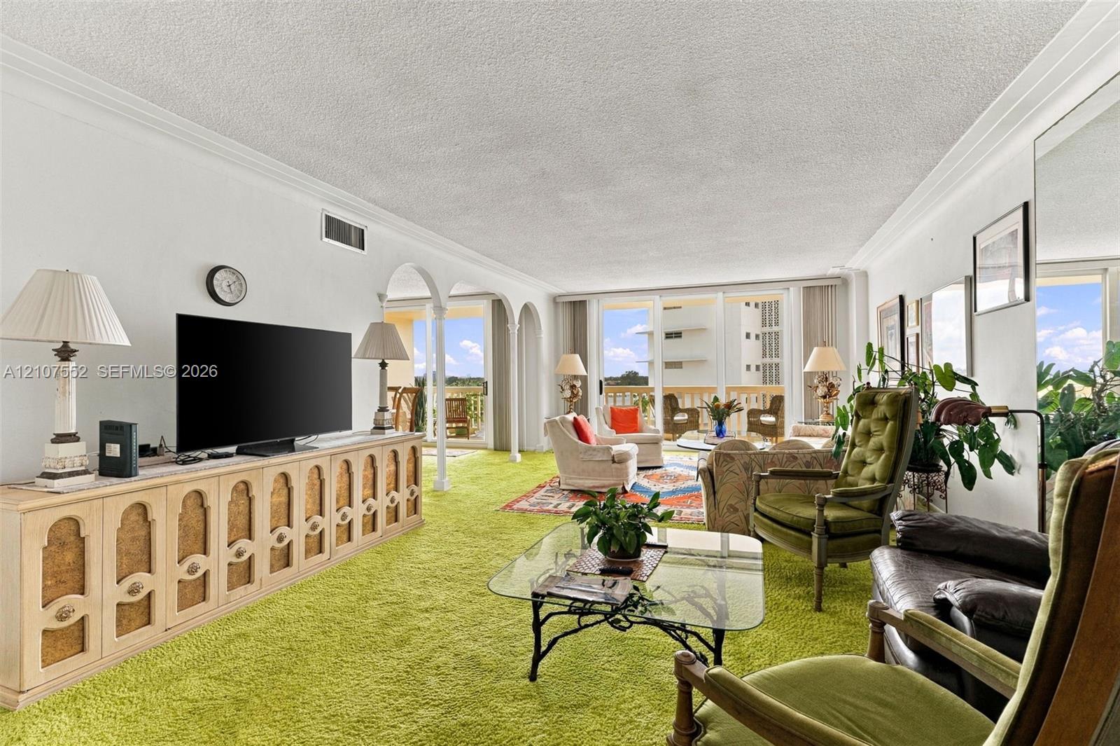Living area featuring crown molding, built-in cabinetry, decorative arched entryways, and floor-to-ceiling glass doors