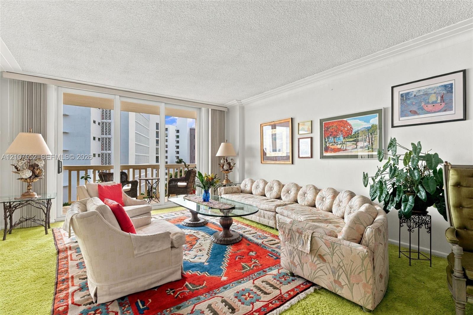 Living area featuring expansive floor-to-ceiling glass sliding doors, private balcony access, and crown molding