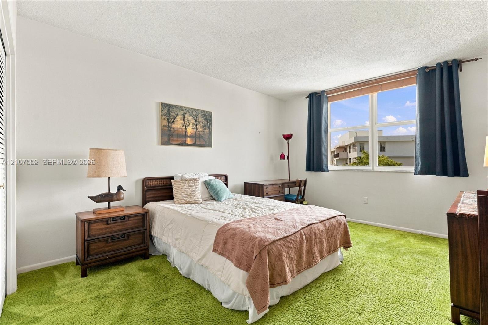 Spacious room featuring neutral wall tones, textured ceiling, and a large window providing natural light