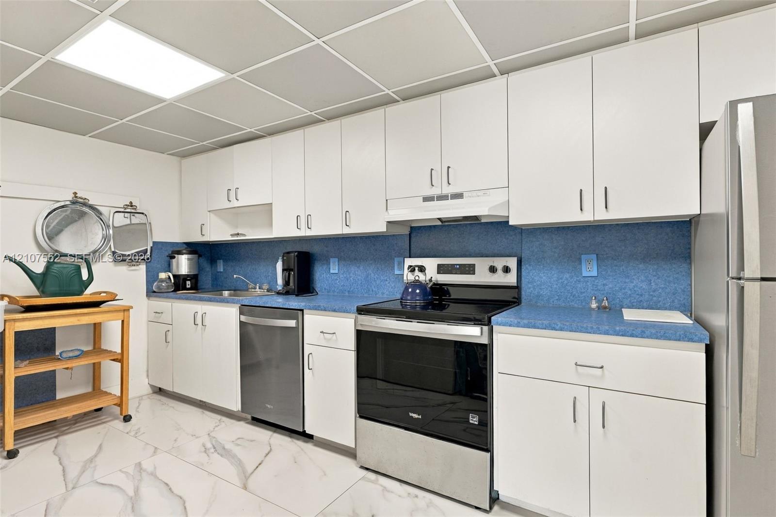 Kitchen featuring white cabinetry, blue countertops, stainless steel appliances, and tile flooring